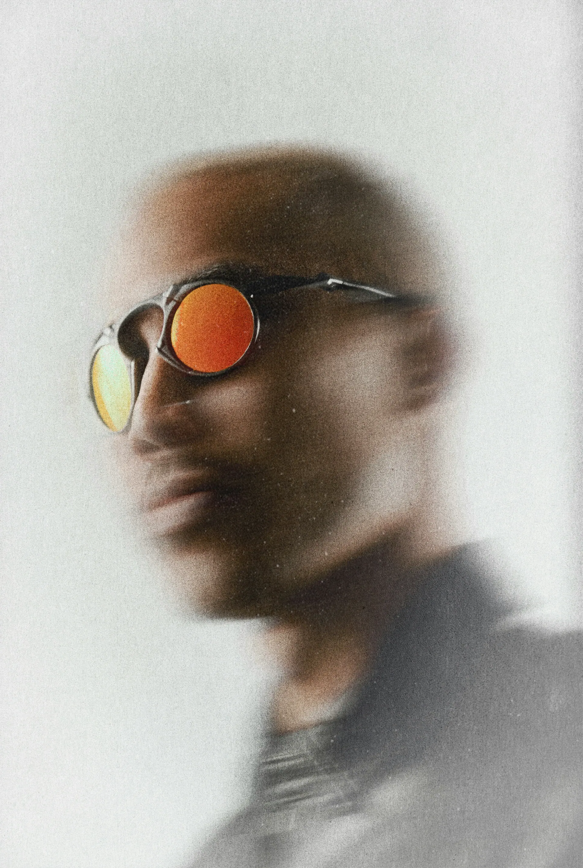 Portrait in motion behind frosted glass, wearing orange lenses